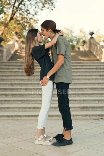 Vista lateral do casal abraçando nas escadas no parque — Fotografia de Stock