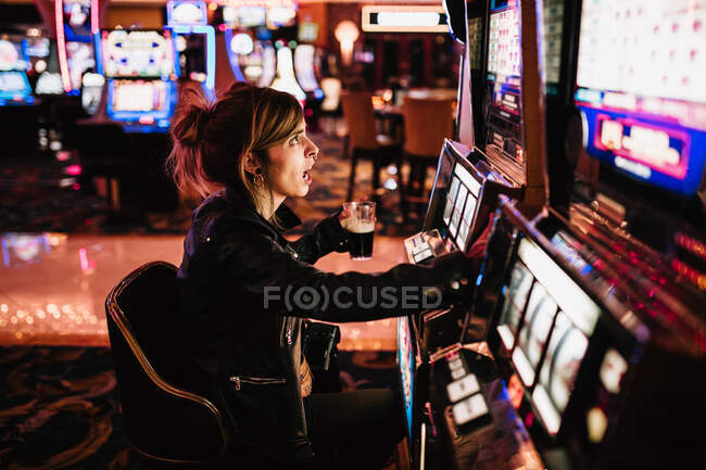Вид збоку жінки, що сидить в казино і грає в ігровий автомат . — стокове фото