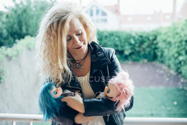 Porträt einer blonden Frau, die mit Puppen posiert und sie ansieht — Stockfoto