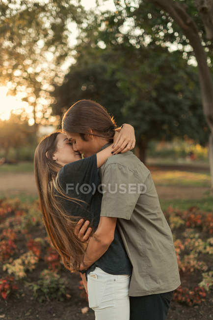 Retrato de jovens abraçando casal beijando no parque — Fotografia de Stock