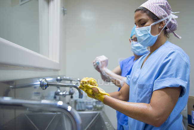 Побочный обзор врачей в униформе, моющих руки перед операцией — стоковое фото