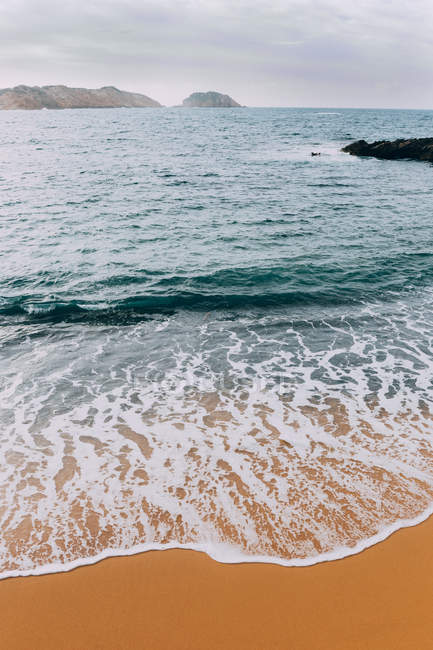 Вид на хвилі на піщаний пляж на спокійній береговій лінії — стокове фото