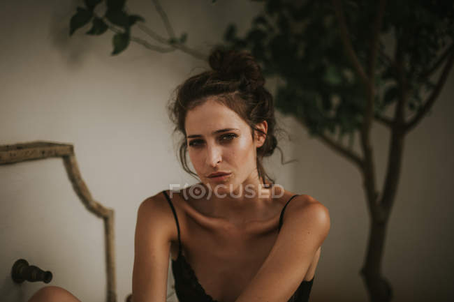 Портрет молодої жінки, яка дивиться на камеру проти розфокусованого дерева — стокове фото