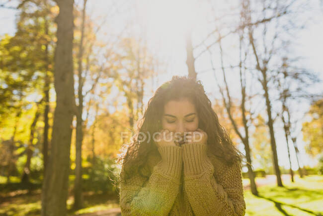 Портрет девушки на расплывчатом фоне, обнимающейся в тёплом свитере — стоковое фото