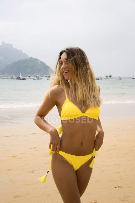 Стройная блондинка в бикини на пляже смотрит в сторону — стоковое фото