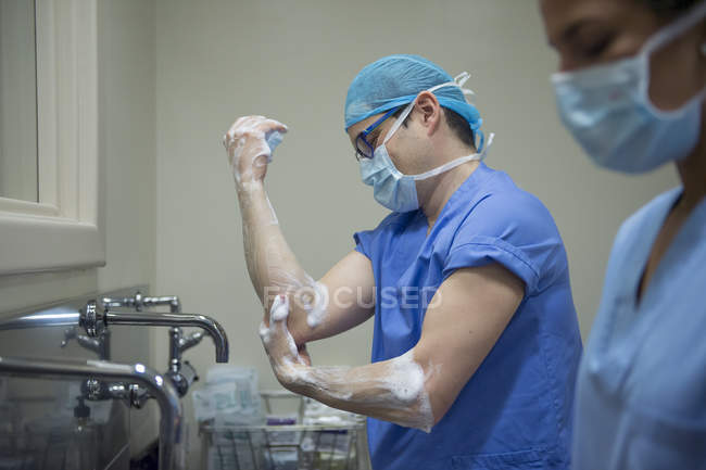 Side view of doctors in uniform washing hands before operation — Stock Photo