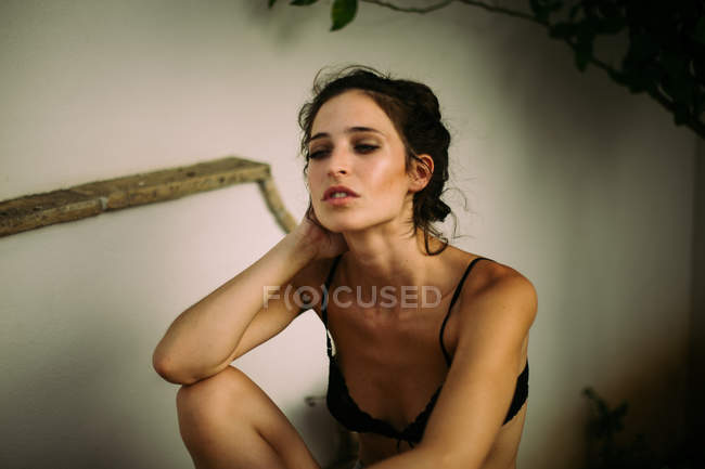 Portrait de femme brune portant de la lingerie noire et regardant loin avec la bouche à moitié ouverte — Photo de stock
