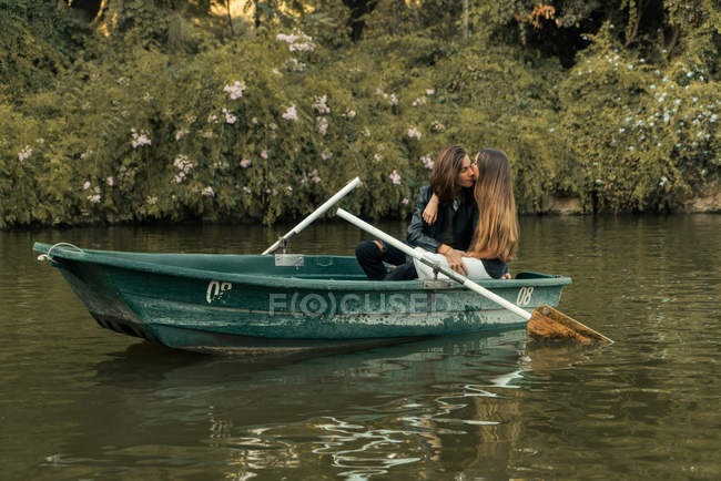 Casal sensual abraçando no barco no lago sobre arbustos no fundo — Fotografia de Stock