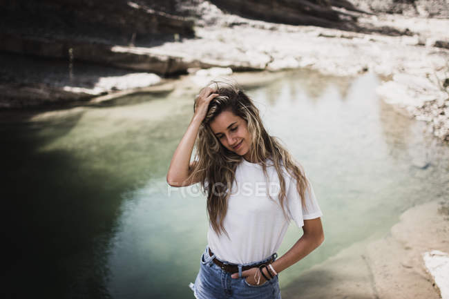 Femme blonde souriante debout au lac — Photo de stock
