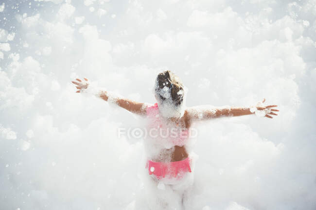 Girl playing in foam outside — Stock Photo