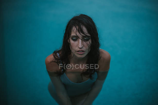 Retrato de mujer en camiseta mojada posando en piscina - foto de stock