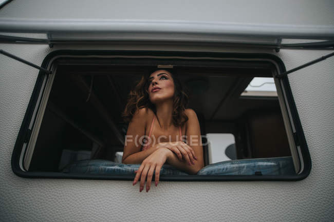 Жінка в мереживному бюстгальтері дивиться з вікна трейлера — стокове фото