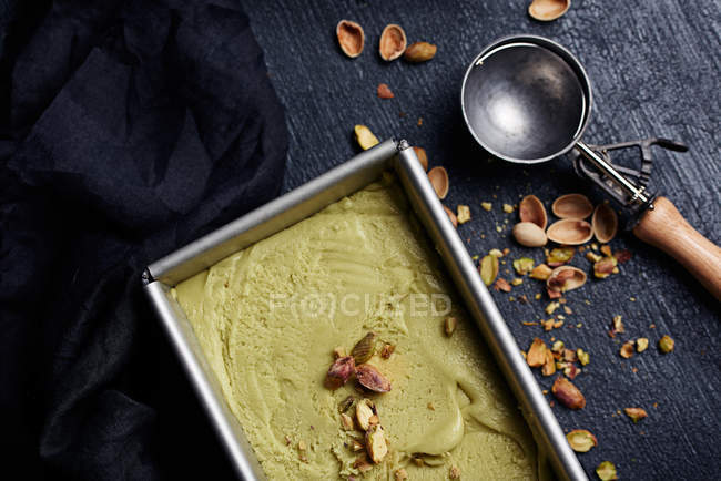 Recipiente de arriba con helado de pistacho y cuchara - foto de stock