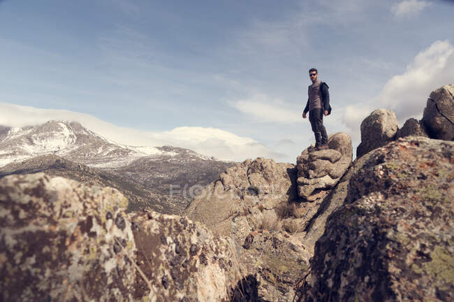 Людина на вершині гори насолоджується захопленим вітром у сонячний зимовий день — стокове фото