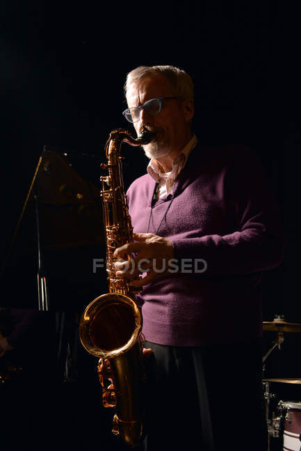 Зрілий чоловік грає на саксофоні з закритими очима — стокове фото
