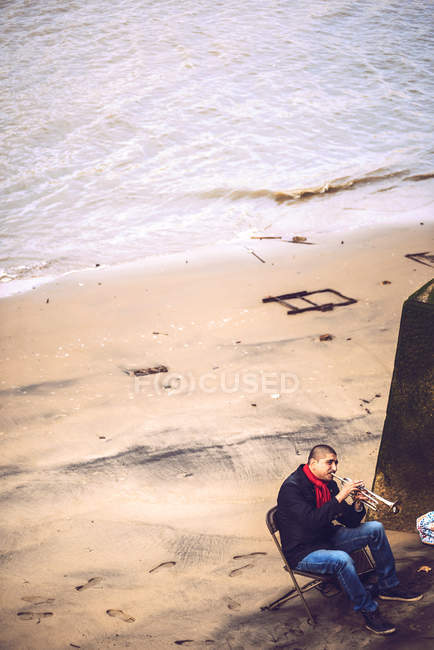LONDRA, Regno Unito - 14 OTTOBRE 2016: Musicista seduto sulla sedia pieghevole e che suona la sua tromba alla riva del Tamigi, Londra — Foto stock