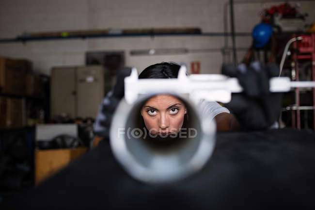 Porträt einer Mechanikerin, die durch die Röhre in die Kamera blickt — Stockfoto