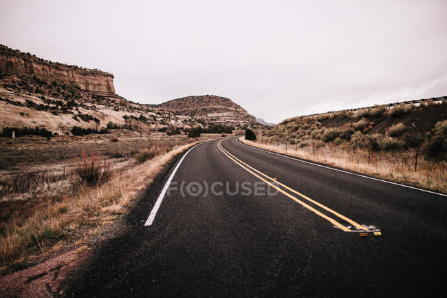 Estrada deserta vazia contra o céu cinzento — Fotografia de Stock