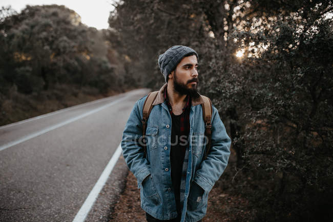 Uomo con zaino a piedi sulla strada di campagna e guardando da parte — Foto stock
