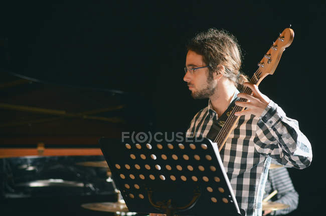 Uomo dai capelli lunghi che suona il basso sul palco — Foto stock