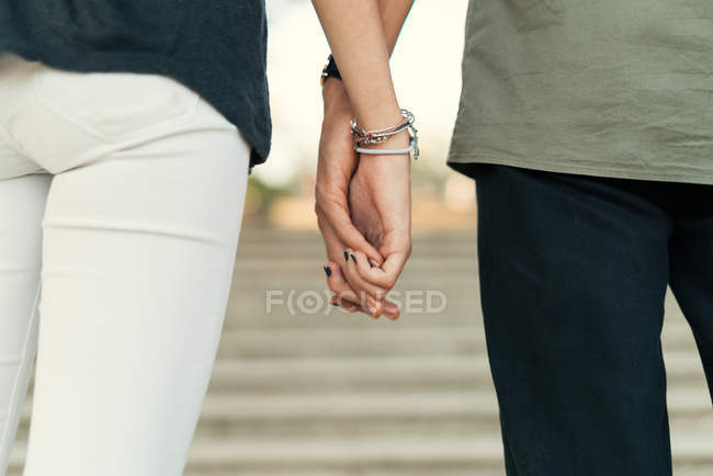 Récolte de couple montant les escaliers et tenant les mains ensemble — Photo de stock