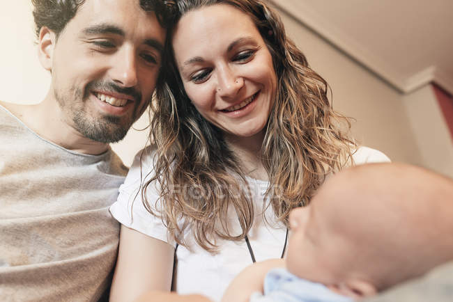 Щаслива молода пара дивиться на новонародженого сина — стокове фото
