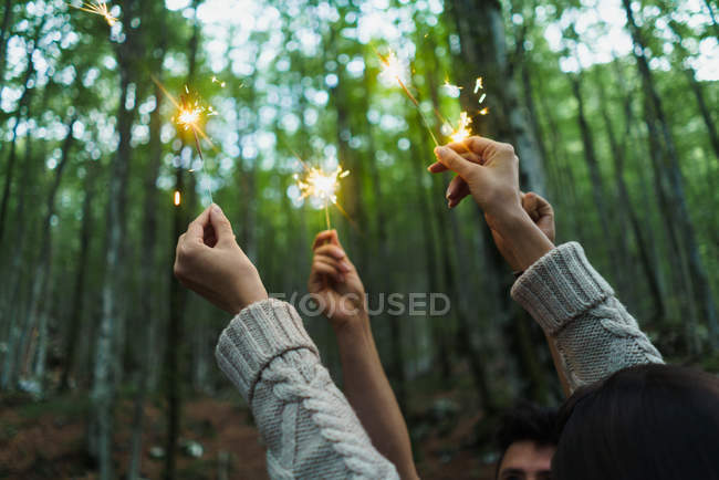 Hands with sparklers in woods — Stock Photo