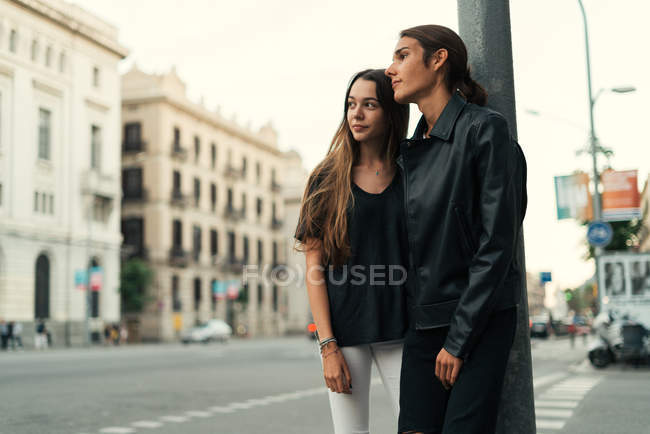 Retrato de pareja abrazada apoyada en el poste en la calle - foto de stock