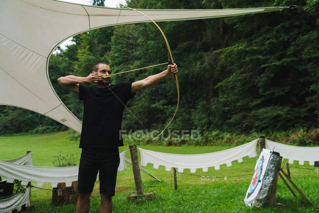 Side view of man practicing archery outdoor — Stock Photo