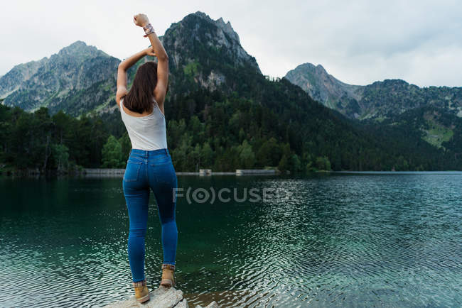 Mujer posando sobre piedra en el lago de montaña - foto de stock