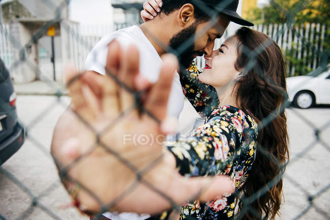 Поцілунки пара спирається на паркан — стокове фото