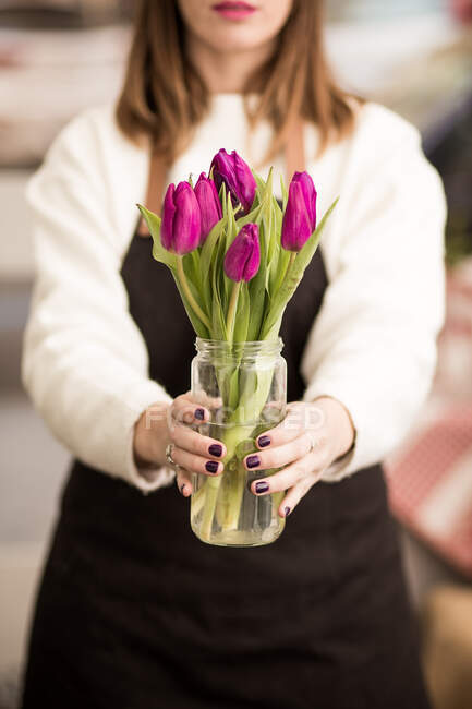 Woman holding fresh pink tulips in jar — Stock Photo