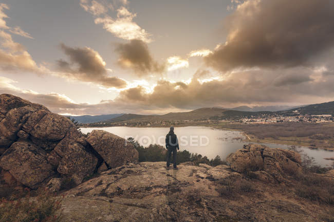 Mann beobachtet Sonnenuntergang am See von der Spitze des Hügels — Stockfoto