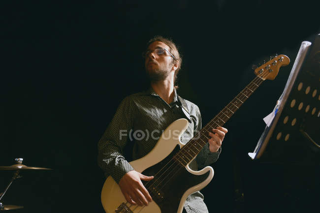 Bass player in stage against black — Stock Photo
