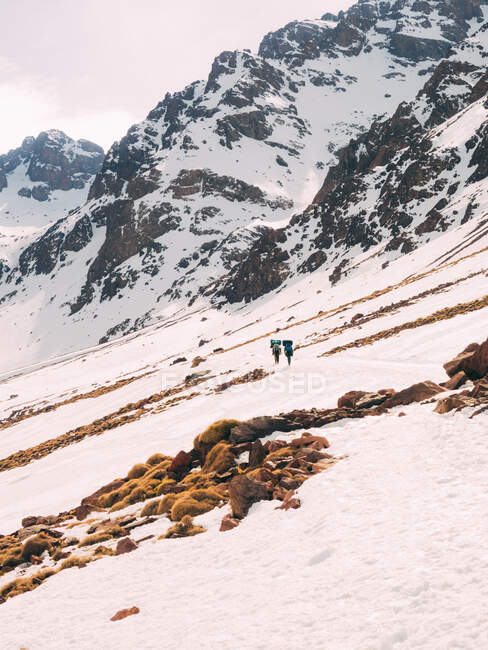 Les gens marchent sur la pente enneigée des montagnes — Photo de stock