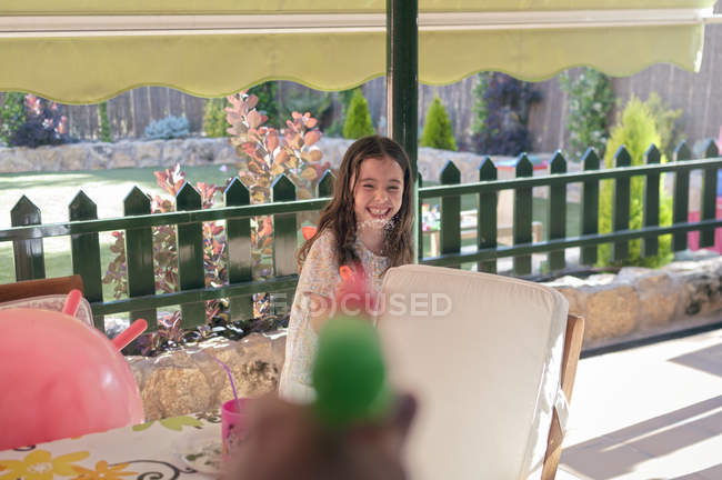 Crop hand shooting water with toy gun at cheerful girl — Stock Photo