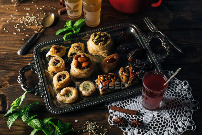 Délicieux dessert knafeh sur assiette avec menthe et verres de thé — Photo de stock