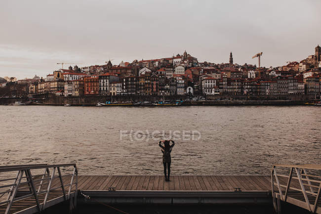 Rear view of female traveler at riverside against of old town — Stock Photo
