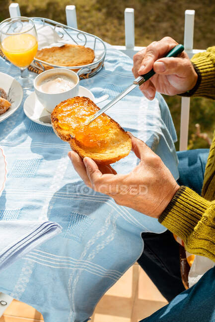 Cropped image of man making toast at table — Stock Photo