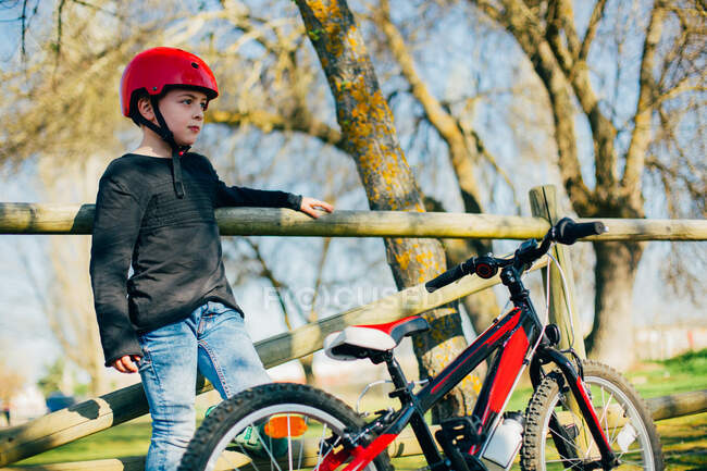 Garçon se reposant après avoir monté son vélo dans le parc — Photo de stock