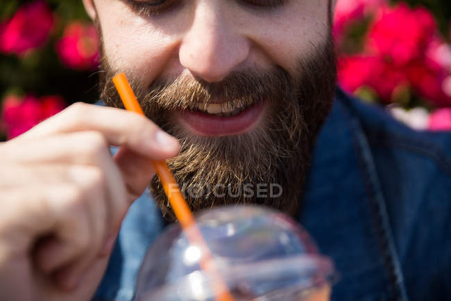 Cultiver homme barbu regardant dans le verre avec smoothie — Photo de stock