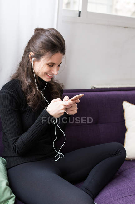 Porträt eines brünetten Mädchens mit Kopfhörern, das im Bus sitzt und auf dem Smartphone surft — Stockfoto