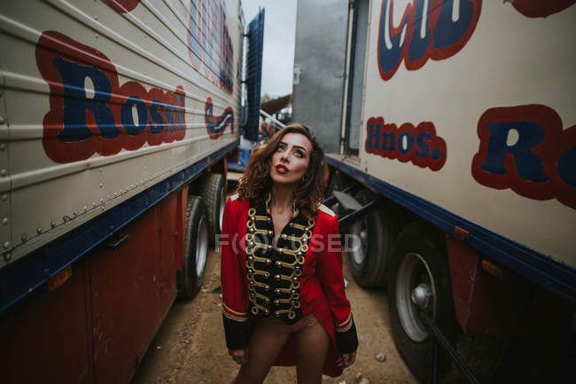 Mujer con abrigo rojo y posando entre remolques - foto de stock