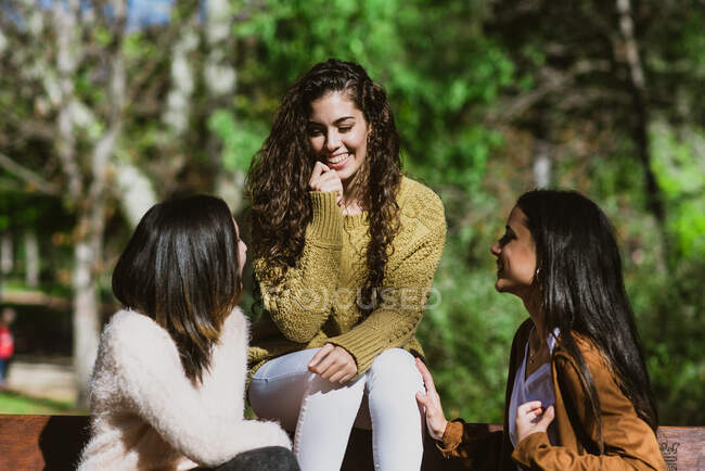 Retrato de três jovens mulheres conversando no parque — Fotografia de Stock