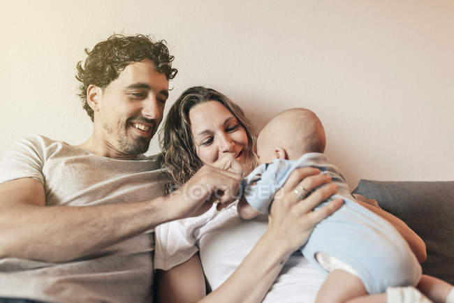 Couple heureux avec bébé nouveau-né en entraîneur à la maison — Photo de stock