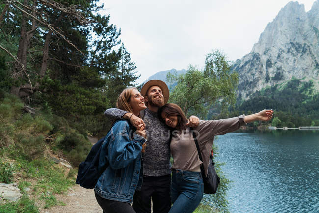 Trois amis câlins sur le lac de montagne — Photo de stock