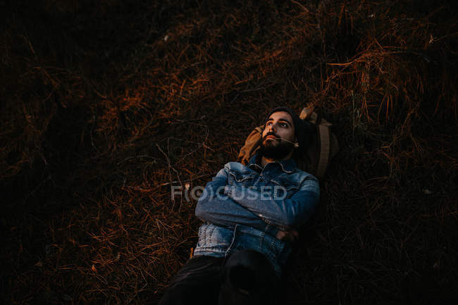 El hombre barbudo que yace en el suelo en el bosque - foto de stock