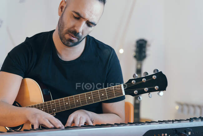 Молодой человек записал гитары и фортепиано в своей домашней звуковой студии. — стоковое фото