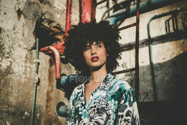 Ritratto di bella ragazza con afro posa in fabbrica abbandonata — Foto stock