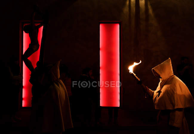 Side view of people in white hoods walking with torch at night street — Stock Photo